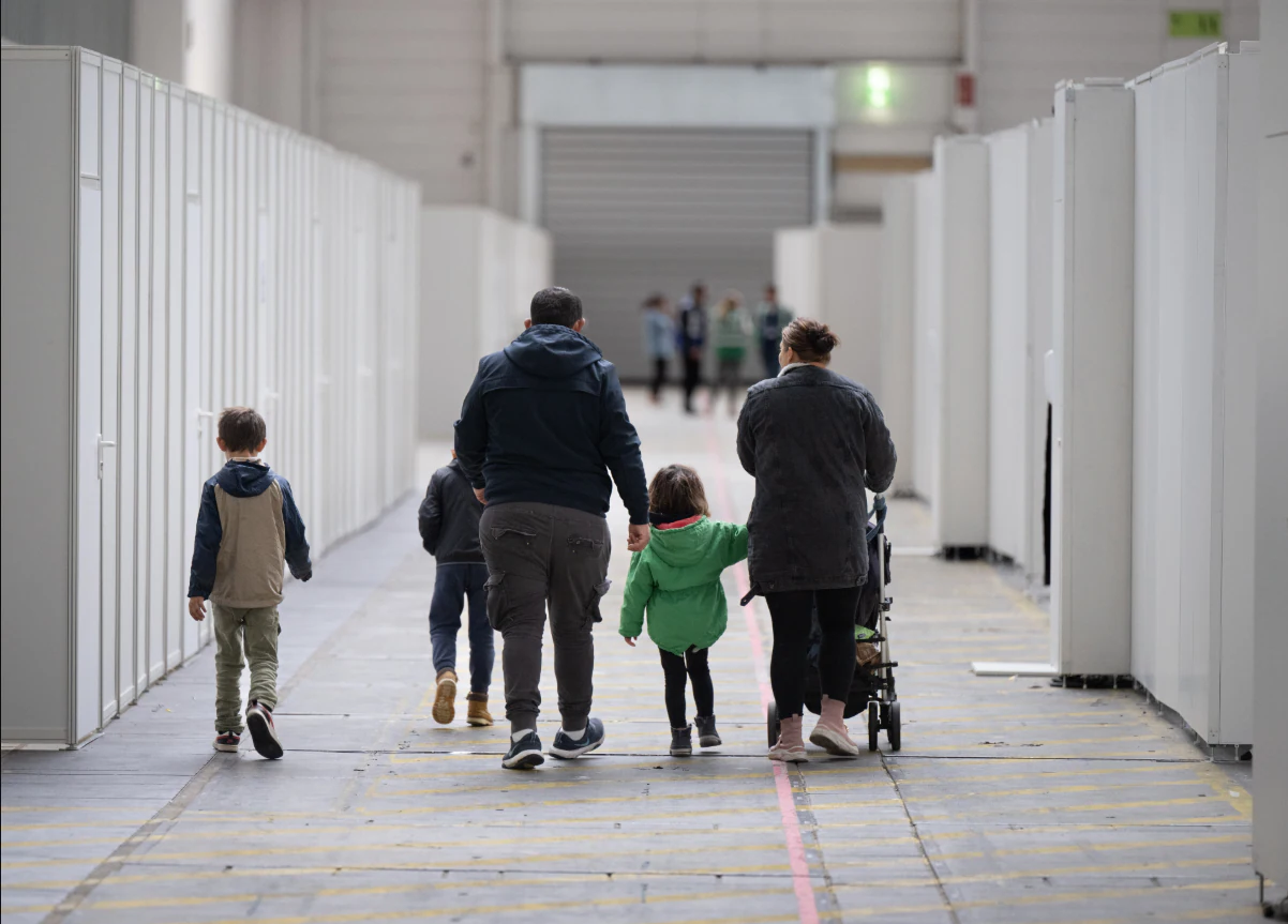 Eine Flüchtlingsfamilie geht durch die zu einer Massenunterkunft umfunktionierten Messehalle in Frankfurt.